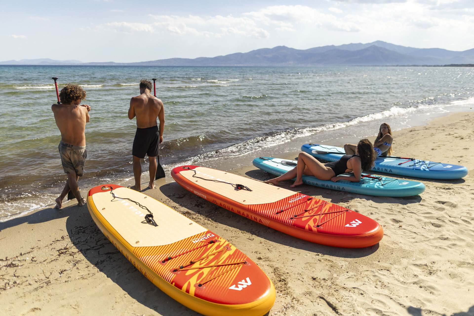 Priprema SUP daske za izlazak s plaže na more Ljudi i šarene SUP daske na pješčanoj plaži